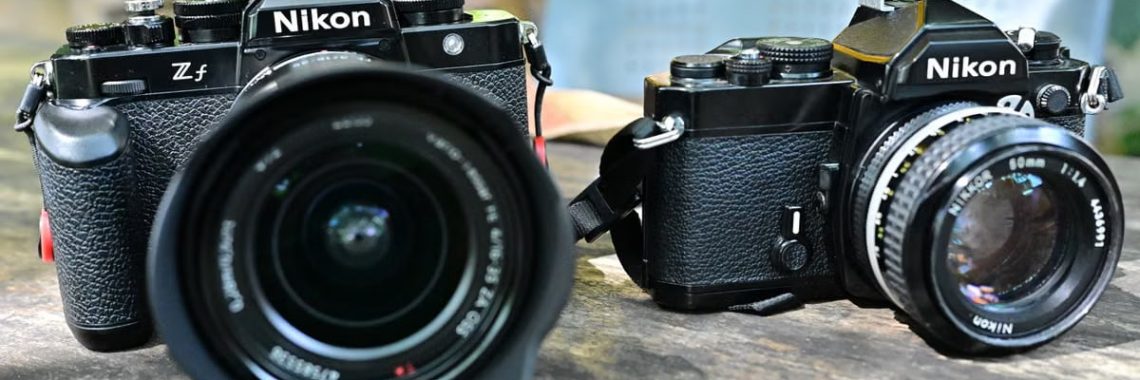 A detailed shot of two vintage Nikon cameras placed outdoors on a table.